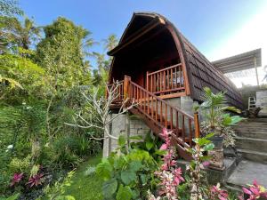 een huis met een balkon en een aantal planten en bloemen bij Sugita Wooden House in Payangan