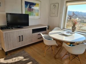 Una sala de estar con televisión, mesa y sillas. en appartement Ideaal, en Bergen aan Zee