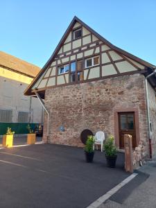 EbersmunsterGîte de l'Abbatiale,3 étoiles, dans une grange du XVIIIème ,1 à 6 personnes的前面有白色椅子的砖砌建筑