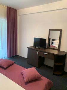 a hotel room with a desk and a mirror at Pensiune Restaurant Piatra Craiului in Dîmbovicioara