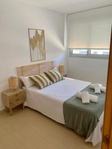sypialnia z dużym białym łóżkiem i oknem w obiekcie Precioso apartamento primera línea de playa w mieście Águilas