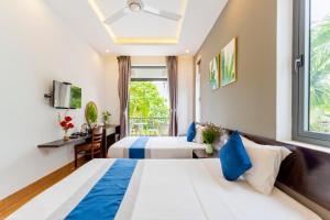 a hotel room with two beds and a window at Villa Charming Hoi An in Hoi An