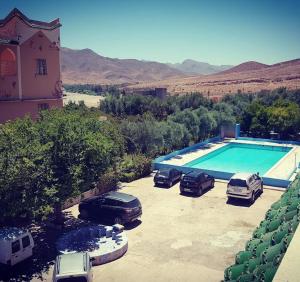 dois carros estacionados num parque de estacionamento ao lado de uma piscina em Auberge Restaurant Targa Taliouine em Taliouine