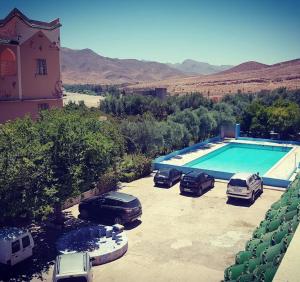 zwei Autos auf einem Parkplatz neben einem Pool geparkt in der Unterkunft Auberge Restaurant Targa Taliouine in Taliouine