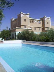 - un grand bâtiment avec une piscine en face dans l'établissement Auberge Restaurant Targa Taliouine, à Taliouine