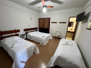 a hotel room with two beds and a ceiling fan at Pousada Giramundo in Teixeiras