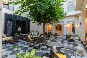 une cour avec des tables, des chaises et un arbre dans l'établissement Kaner Bagh A Heritage Boutique Hotel, à Udaipur