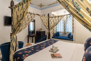 a bedroom with a bed and a table and a window at Kaner Bagh A Heritage Boutique Hotel in Udaipur