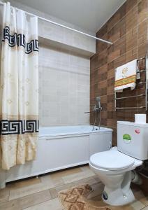 uma casa de banho com um WC e uma cortina de chuveiro em Уютная квартира в г.Алматы em Almaty