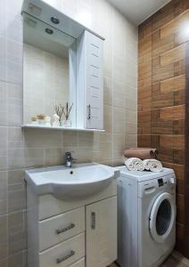 uma casa de banho com um lavatório e uma máquina de lavar roupa em Уютная квартира в г.Алматы em Almaty