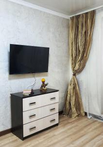 um quarto com uma cómoda e uma televisão na parede em Уютная квартира в г.Алматы em Almaty