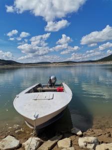a white boat sitting on the shore of a lake at Zlatar Lake - cottage in Kokin Brod