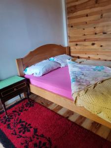 a bedroom with a wooden bed with a red rug at Zlatar Lake - cottage in Kokin Brod
