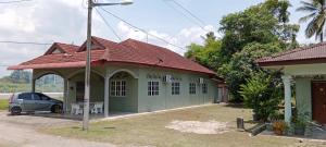 a green building with a car parked in front of it at Homestay Hassani in Kepala Batas