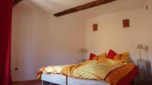 a bedroom with a bed with orange sheets and red pillows at L'Esprit du vallon de Berlou in Berlou