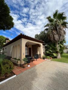 a house with a patio and a palm tree at Chalet en La Barrosa, Piscina+BBQ+Grifo de Cerveza in Chiclana de la Frontera