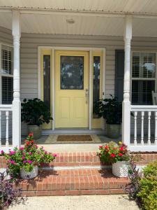 a yellow front door of a house with flowers at Suite Melissa's Pinehurst Country Club #6 Private Room and Bath in Pinehurst