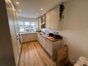 a kitchen with white cabinets and a wooden floor at DAIRY COTTAGE WHITBY in Whitby