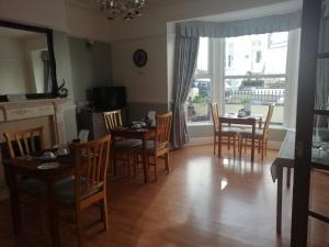 un comedor con mesas y sillas y una gran ventana en No 6 Quality Guesthouse en Llandudno