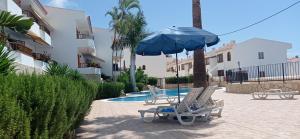 two lounge chairs and an umbrella next to a pool at HC home abroad Costa Adeje in Adeje