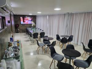 uma sala de jantar com mesas e cadeiras e uma televisão em Recanto Convenções em Olinda