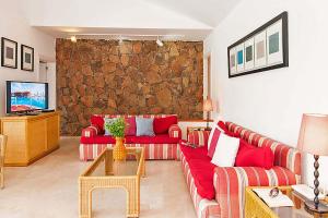 Chalet Isabel في ماسبالوماس: غرفة معيشة بها أرائك حمراء وجدار حجري