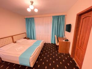 フネドアラにあるHostel Paltinisのベッドとデスクが備わるホテルルームです。