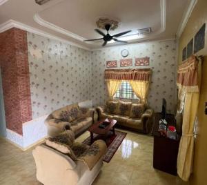 sala de estar con 2 sofás y ventilador de techo en Homestay Hassani en Kepala Batas