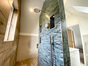 a bathroom with a shower with blue tile on the wall at Trewhiddle Villa 09 in St Austell