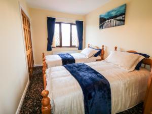 two beds in a room with blue curtains at Derriens Farmhouse in Enniskillen