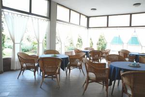 un comedor con mesas, sillas y ventanas en Hotel La Fenice, en Formigine