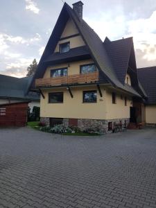 a house with a gambrel roof on a driveway at Pokoje u Micka Poronin 5 km od Zakopanego in Poronin