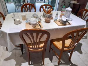 a table with a white table cloth and wooden chairs at CHEZ VIVIANE in Celles-sur-Belle