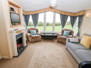 sala de estar con TV, sofá y chimenea en Plas Tirion Caravan en Holyhead