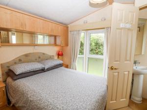 1 dormitorio con cama, lavabo y ventana en Plas Tirion Caravan en Holyhead