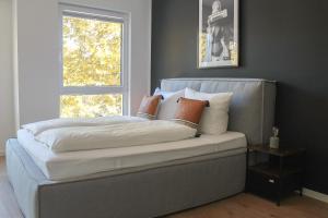 uma cama com almofadas e uma janela num quarto em New York Apartment em Koblenz