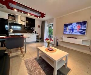 a living room with a table and a tv on the wall at Apartment im Emmental in Oberburg