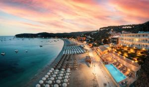 een strand met parasols en boten in het water bij Ionion Beach Resort in Parga