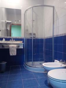 baño de azulejos azules con ducha y aseo en Hotel Venta El Molino, en Alcázar de San Juan