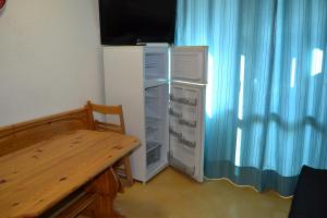 uma cozinha com um frigorífico, uma mesa e uma cortina azul em Appartement Le Vernon em Chamrousse