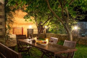 a wooden table in a garden with candles on it at Ifigenia Lux MAISONETTE in oldtown and Villas in theriso vilage 14 km outside of chania in Chania
