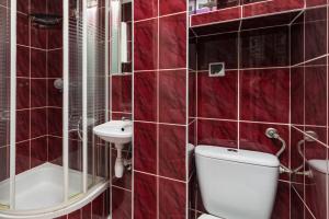 a red tiled bathroom with a toilet and a sink at Anielewicza 49 by Homeprime in Warsaw