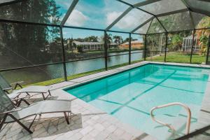 a swimming pool with two chairs and a house at The Basilican in Cape Coral