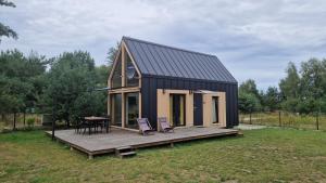 a small black house with a deck and a table at Sasinko Mini in Sasino