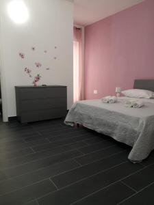 Un dormitorio con paredes rosas y una cama con toallas. en B&B Roseal, en Brusciano