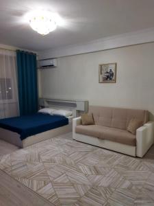 uma sala de estar com um sofá e uma cama em City House em Aktau