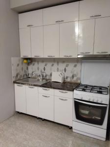 uma cozinha com armários brancos e um forno com placa de fogão em City House em Aktau