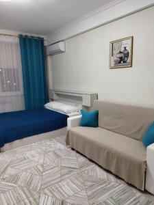 um pequeno quarto com um sofá e uma cama em City House em Aktau