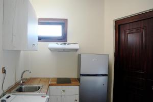 eine kleine Küche mit einem Kühlschrank und einem Fenster in der Unterkunft Giota's Gasthaus in Zakharo