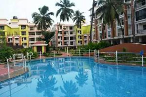 a large swimming pool with palm trees and buildings at 3/4bhk luxury space with pool in Candolim